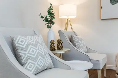 a living room with two chairs and a lamp at Spa Oasis Home - Hot Tub - King Bed - BBQ - Garage - Pets! in Edmonton