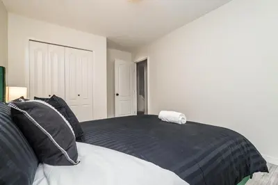 a bedroom with a bed with black and white pillows at Spa Oasis Home - Hot Tub - King Bed - BBQ - Garage - Pets! in Edmonton