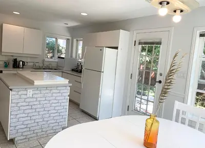 a kitchen with a white refrigerator and a table at One Bedroom queen bed Sharing Washroom in Tiger Sweet House License## in Richmond