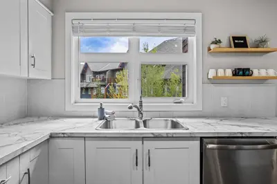 a white kitchen with a sink and a window at CHARMING 1 Bdrm plus loft with VIEWS managed by Little Sister Getaways in Canmore