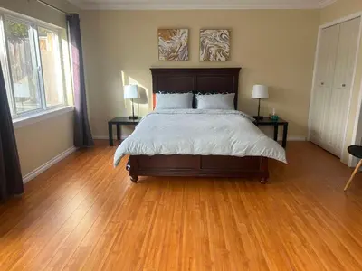 a bedroom with a bed with wooden floors and two lamps at Private Suite with Separated Entrance Monica's Home in Richmond