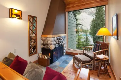 a living room with a fireplace and a large window at Moraine Lake Lodge in Lake Louise