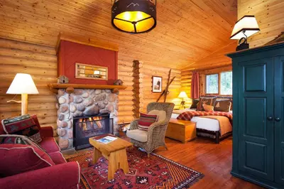 a living room with a fireplace in a log cabin at Cathedral Mountain Lodge in Field