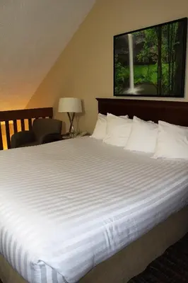 a large bed with white sheets in a hotel room at Ramada by Wyndham Campbell River in Campbell River