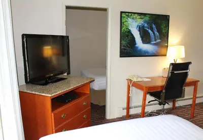 a hotel room with a bed and a desk with a television at Ramada by Wyndham Campbell River in Campbell River