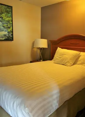 a bedroom with a bed with a white bedspread and a lamp at Ramada by Wyndham Campbell River in Campbell River