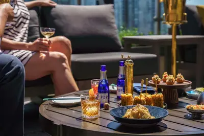 a table with a bowl of food and a woman sitting at The Parker Hotel and Rooftop in Vancouver
