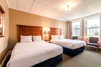 a hotel room with two beds and a chair at The Sylvia Hotel in Vancouver