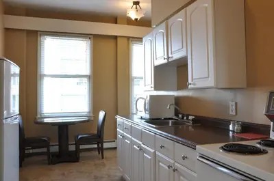 a kitchen with white cabinets and a table and chairs at The Sylvia Hotel in Vancouver