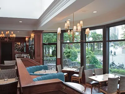 a restaurant with tables and chairs and windows at The Sylvia Hotel in Vancouver