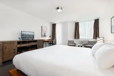 a hotel room with a white bed and a tv at Adara Hotel in Whistler