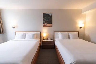 two beds in a hotel room with white sheets at Adara Hotel in Whistler