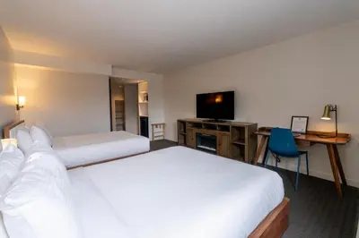 a hotel room with two beds and a desk and a television at Adara Hotel in Whistler