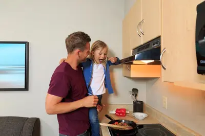 a man holding a little girl in a kitchen at Accent Inns Vancouver Airport in Richmond