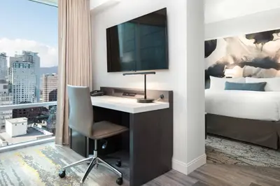 a hotel room with a desk with a television and a bed at Delta Hotels by Marriott Vancouver Downtown Suites in Vancouver