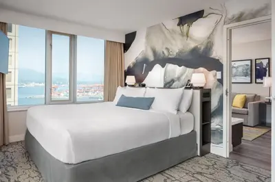 a bedroom with a large white bed with a view at Delta Hotels by Marriott Vancouver Downtown Suites in Vancouver