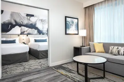 a hotel room with a bed and a couch and a mirror at Delta Hotels by Marriott Vancouver Downtown Suites in Vancouver