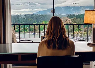 a woman sitting in a chair looking out of a window at The Westin Bayshore, Vancouver in Vancouver