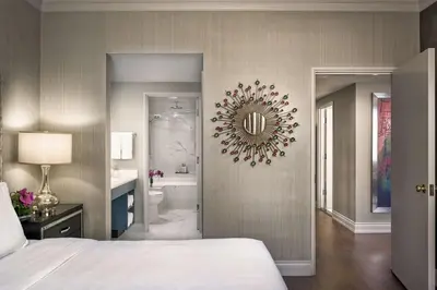 a bedroom with a bed and a bathroom with a mirror at Georgian Court Hotel, WorldHotels Elite in Vancouver