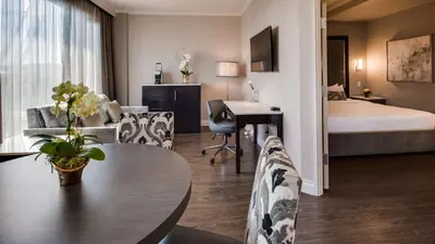 a hotel room with a bed and a table and chairs at Georgian Court Hotel, WorldHotels Elite in Vancouver