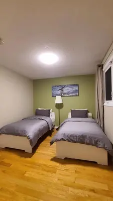 two beds in a room with green walls and wooden floors at YK Aurora in Yellowknife