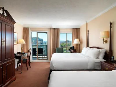 a hotel room with two beds and a desk at Hotel Grand Pacific in Victoria