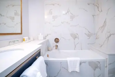 a white bathroom with a tub and a sink at The Sutton Place Hotel Vancouver in Vancouver