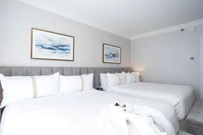 two beds in a hotel room with white pillows at The Sutton Place Hotel Vancouver in Vancouver