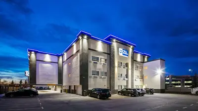 a large building with cars parked in a parking lot at Best Western Airport Inn in Calgary