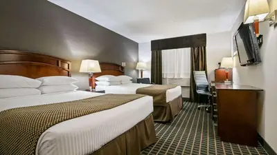 a hotel room with two beds and a flat screen tv at Best Western Airport Inn in Calgary