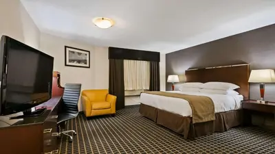 a hotel room with a bed and a flat screen tv at Best Western Airport Inn in Calgary