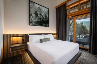 a bedroom with a white bed and a large window at Nita Lake Lodge in Whistler
