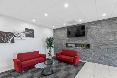 a waiting room with two red chairs and a tv at Emerald Hotel & Suites Calgary Airport in Calgary