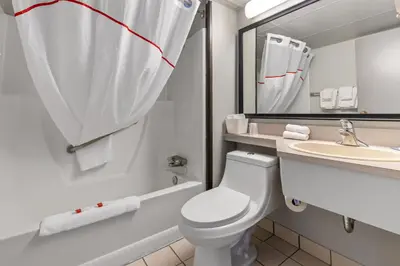 a bathroom with a toilet and a sink and a mirror at Emerald Hotel & Suites Calgary Airport in Calgary