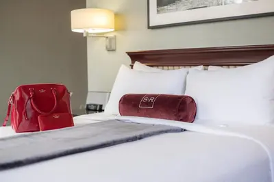 a hotel room with a white bed with a red bag on it at The St. Regis Hotel in Vancouver