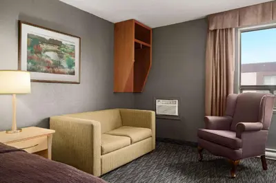 a hotel room with a couch and a chair and a bed at Travelodge by Wyndham Edmonton West in Edmonton