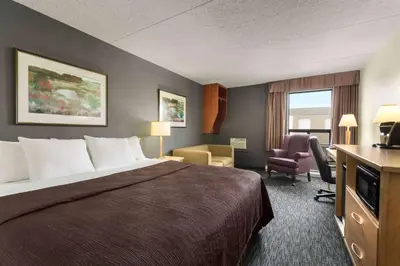 a hotel room with a large bed and a chair at Travelodge by Wyndham Edmonton West in Edmonton