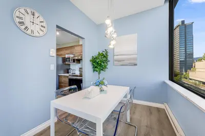 a white dining room with a white table and chairs and a clock at Best Location Downtown Chic Suites in Vancouver