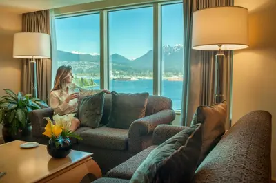 a woman sitting on a couch in a room with a window at Pan Pacific Vancouver in Vancouver