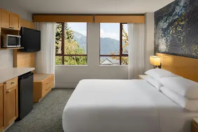 a hotel room with a bed and a large window at Delta Hotels by Marriott Whistler Village Suites in Whistler