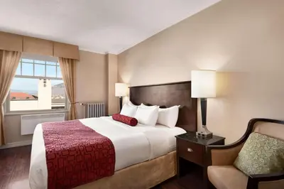 a hotel room with a bed and a chair at The Plaza Hotel Downtown, Trademark Collection by Wyndham in Kamloops