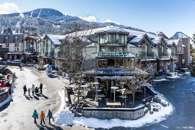 a group of people walking in the snow in front of a building at The Crystal Lodge in Whistler