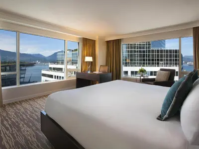 a hotel room with a bed and a large window at Fairmont Waterfront in Vancouver