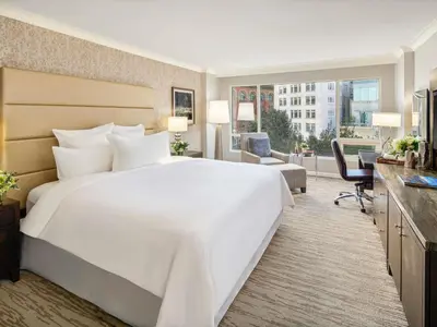 a hotel room with a large white bed and a desk at Fairmont Waterfront in Vancouver