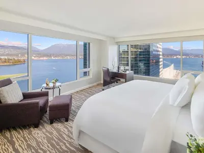 a hotel room with a large bed and large windows at Fairmont Waterfront in Vancouver