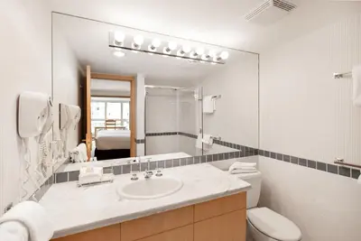 a bathroom with a sink and a toilet and a mirror at Le Chamois by Whistler Premier in Whistler