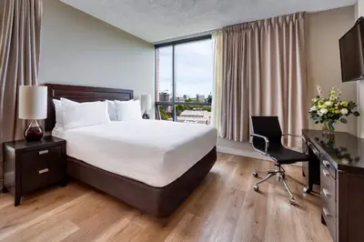 a hotel room with a bed and a desk and a window at Oswego Hotel in Victoria