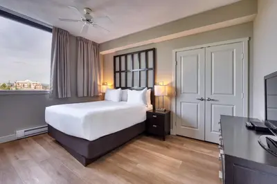 a bedroom with a white bed and a large window at Oswego Hotel in Victoria