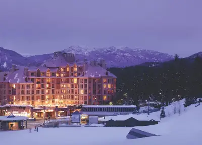 a large building in the snow at night at Pan Pacific Whistler Mountainside in Whistler