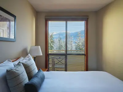 a bedroom with a large bed and a large window at Pan Pacific Whistler Mountainside in Whistler
